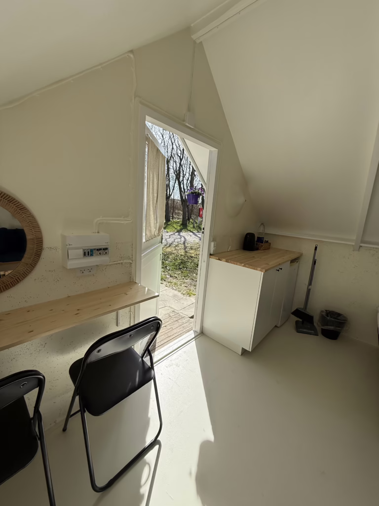 Indgang til lille campinghytte med blomster ved døren